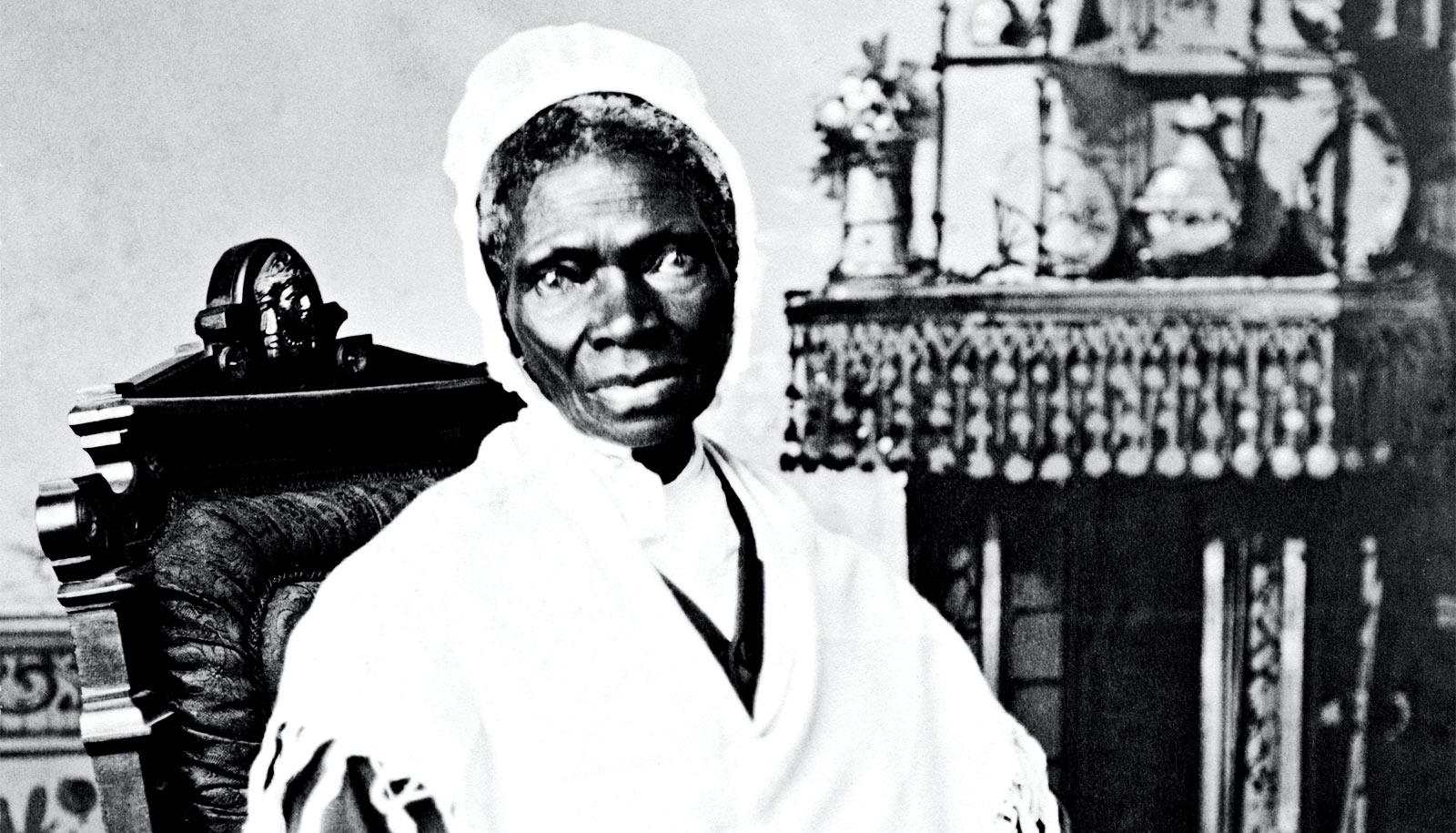 Sojourner Truth sits in a chair looking at the camera, wrapped in a white shawl