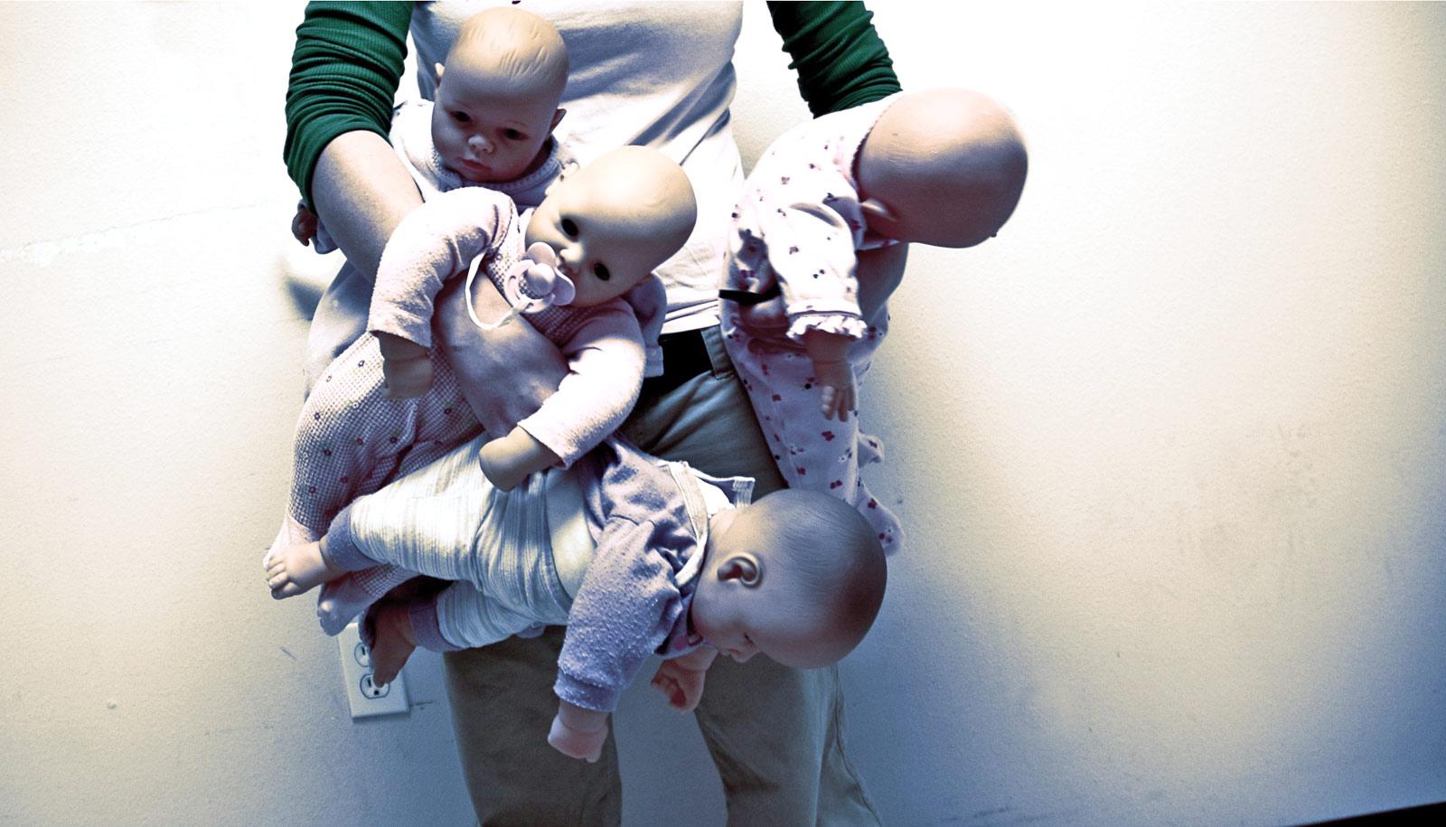 person holding four baby dolls