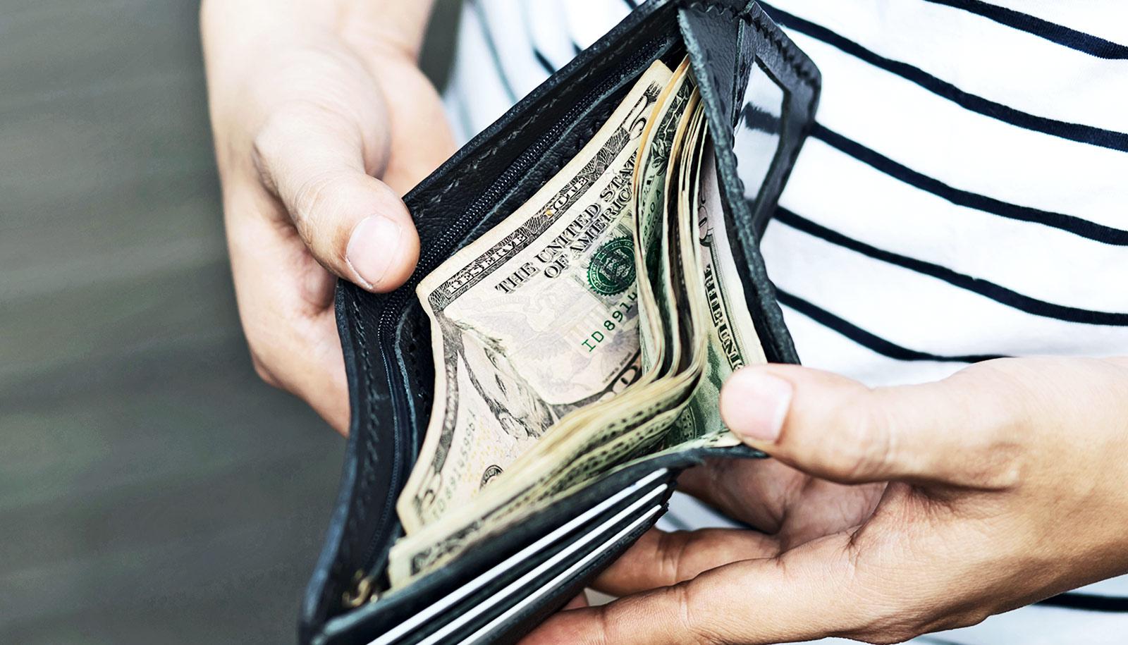 A man looks into his wallet at some cash