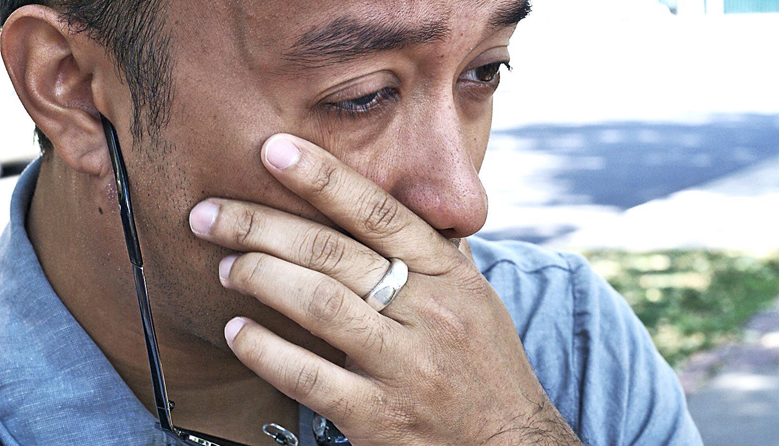 A man puts his hand to his face and looks stressed