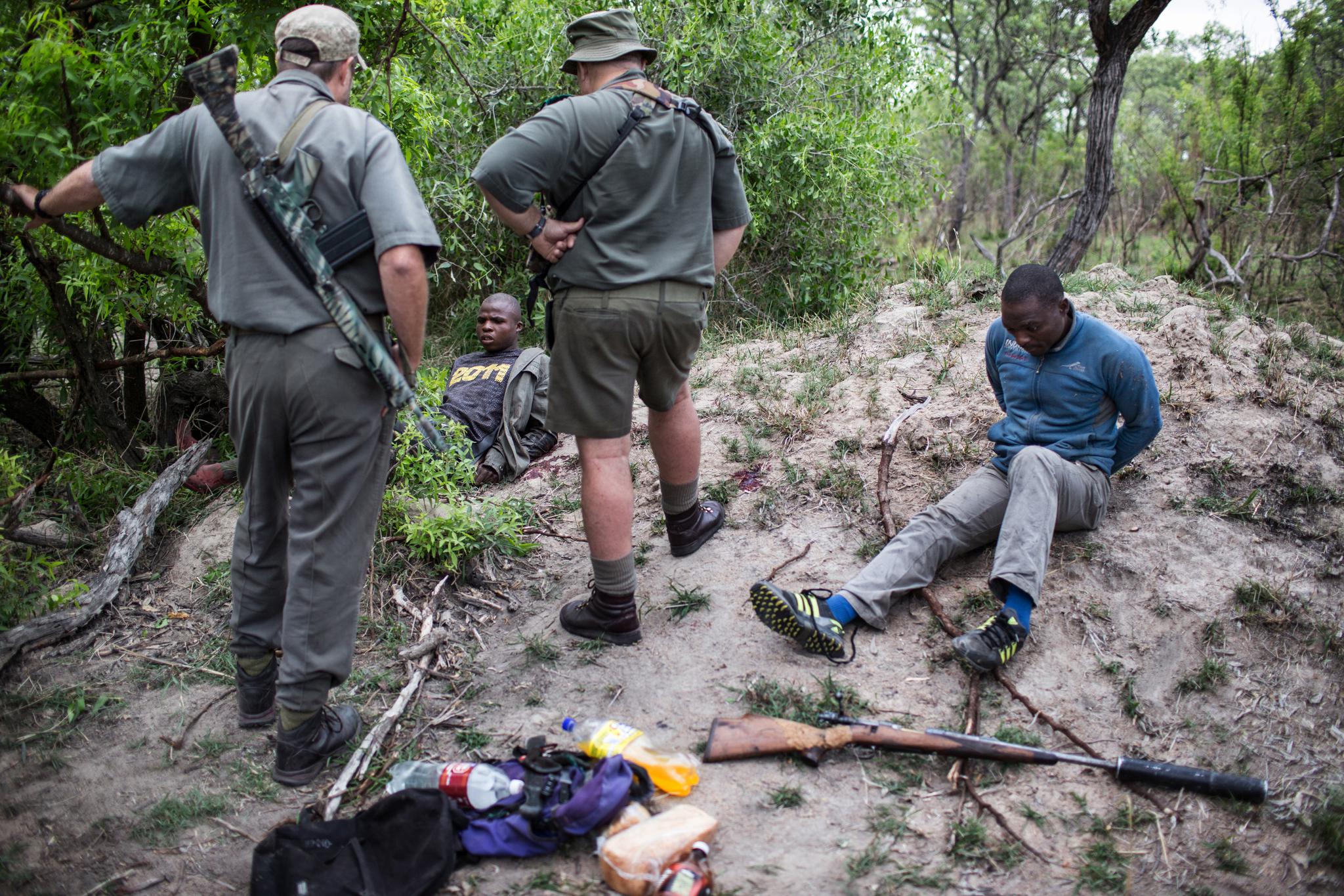 Rangers Rob Thompson and Don English with suspected rhino poachers at Kruger National Park in South Africa, on November 7, 2014.