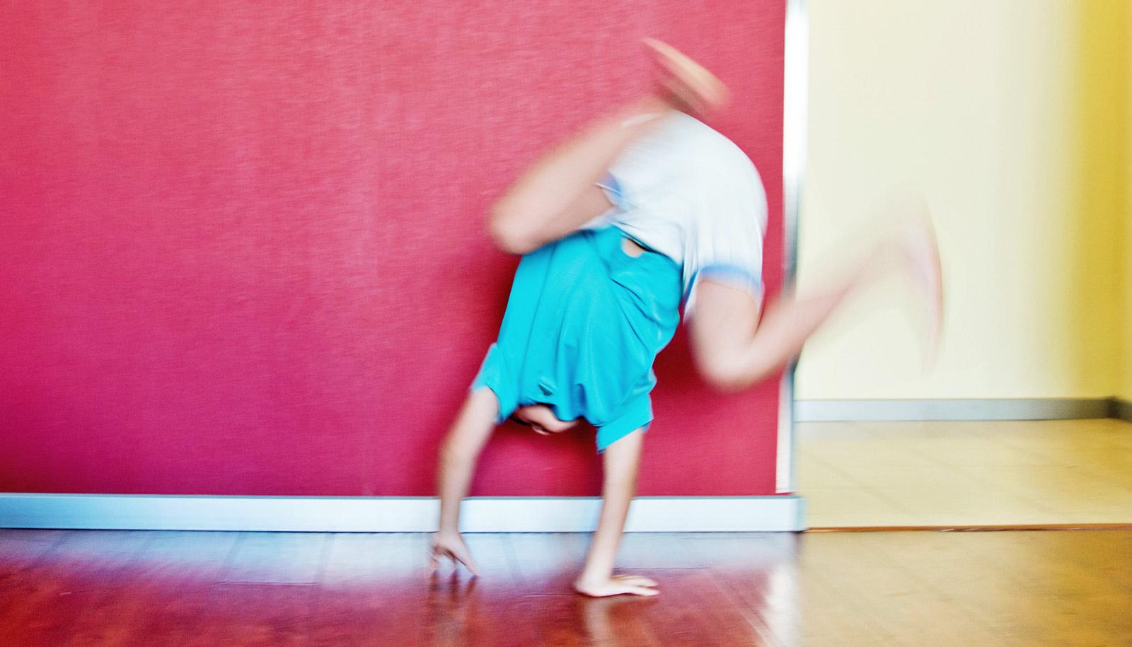 boy does handstand against red wall