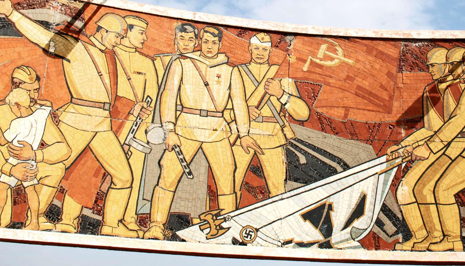 Russian war memorial shows Soviet soldiers in tan uniforms taking down Nazi flags and holding up the Soviet banner.