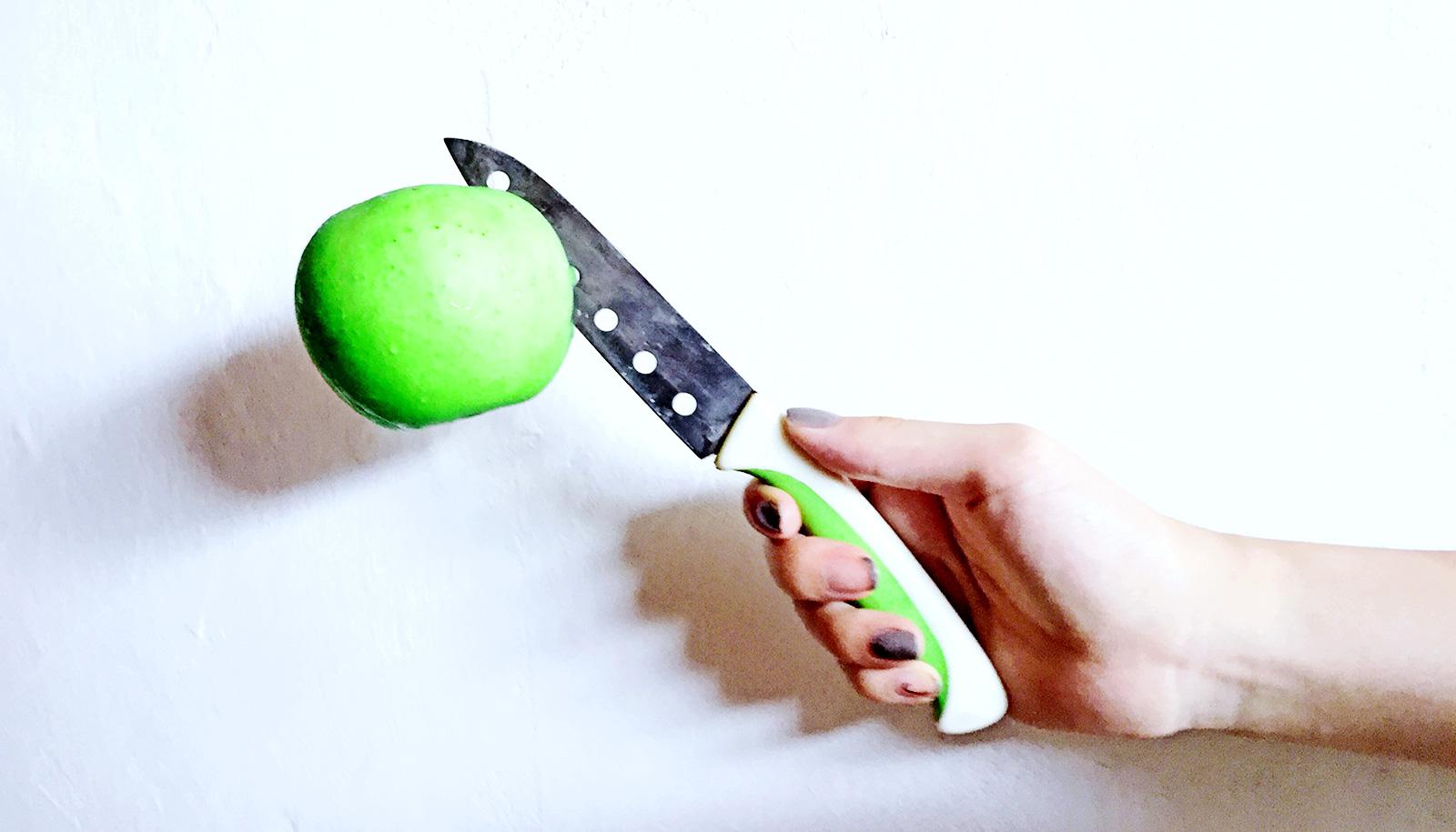 knife in apple in hand (food choices concept)