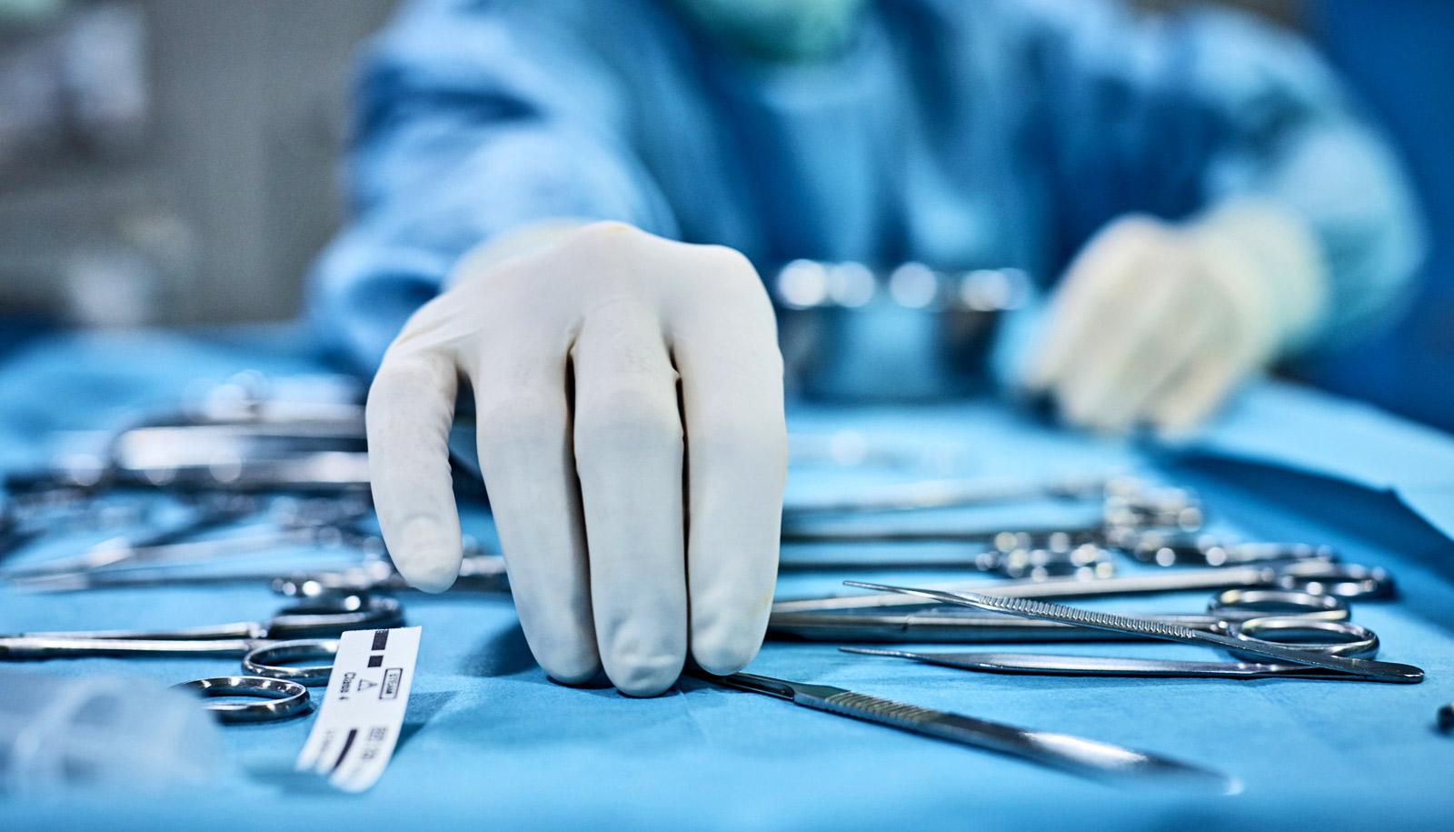 surgeon picks up tool from tray