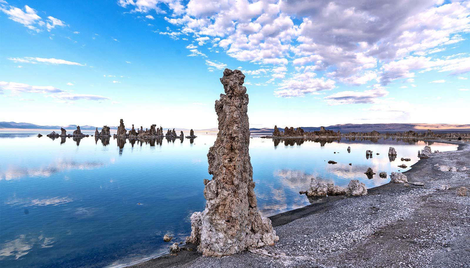 A bright blue lake reflects the blue, cloudy sky at