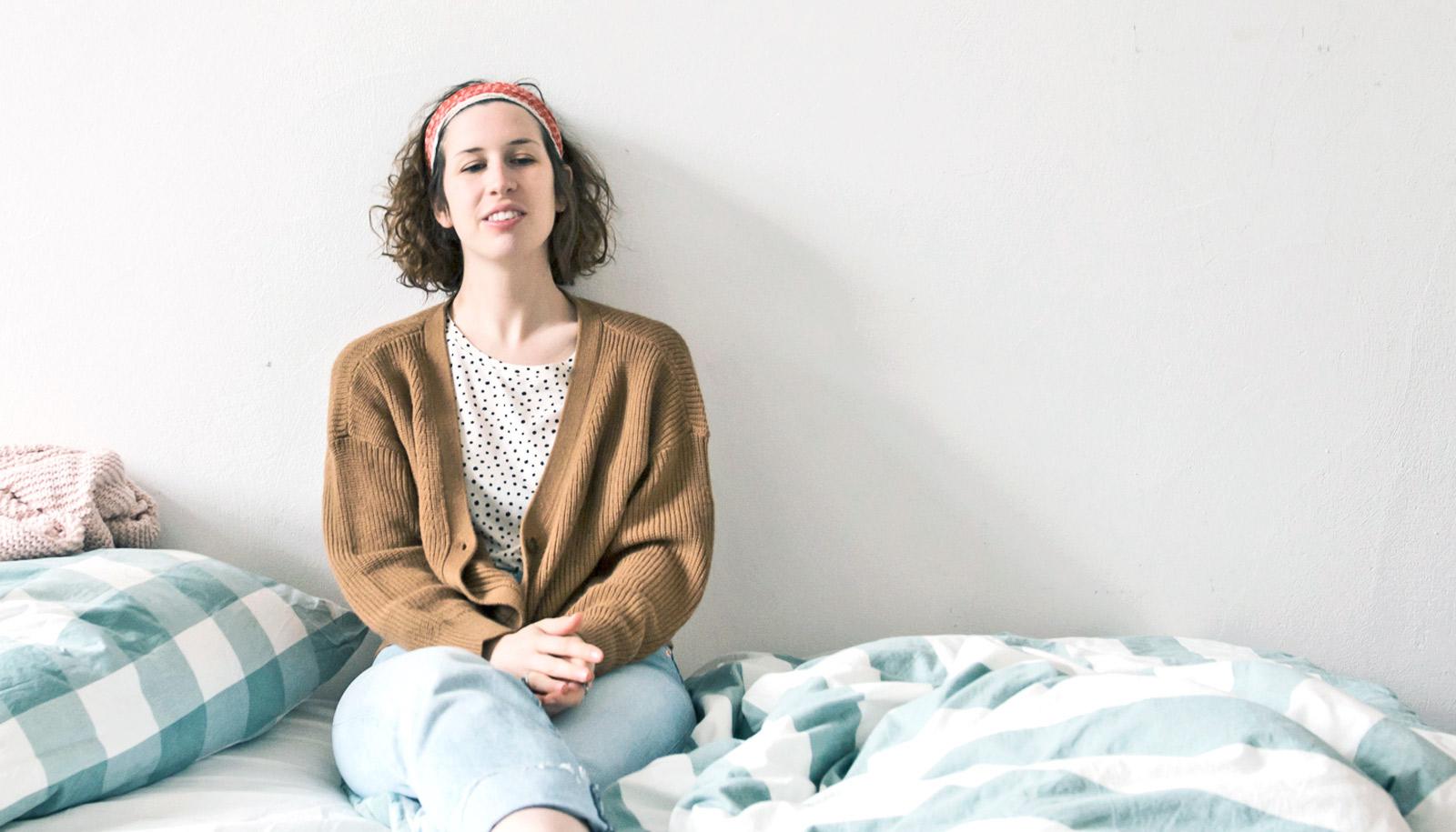 young woman sits on bed - first-year students