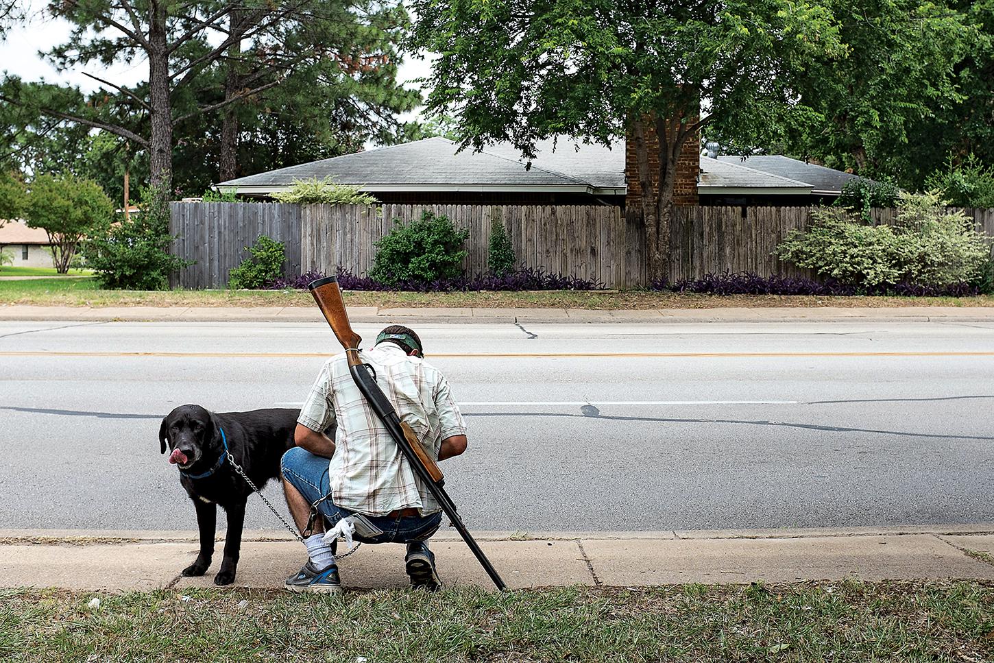 Michael Forster Jr. with his dog and his Remington shotgun during an open carry demonstration in Irving, Texas, on June 21, 2014.