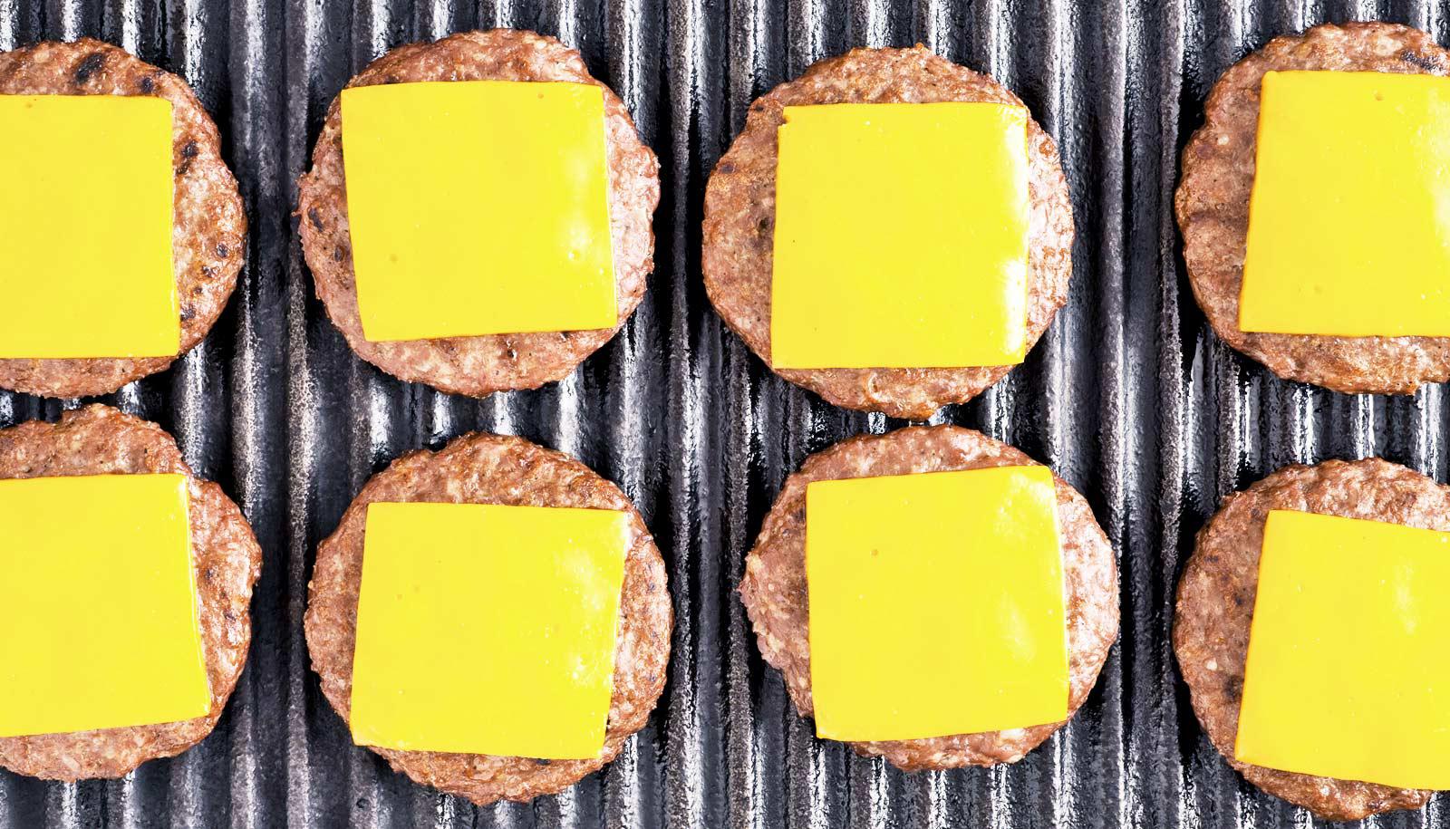 two rows of cheeseburgers on griddle