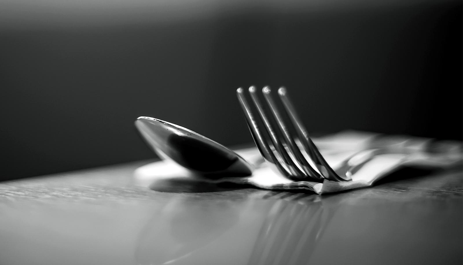 A black and white shot of a fork and spoon on a table