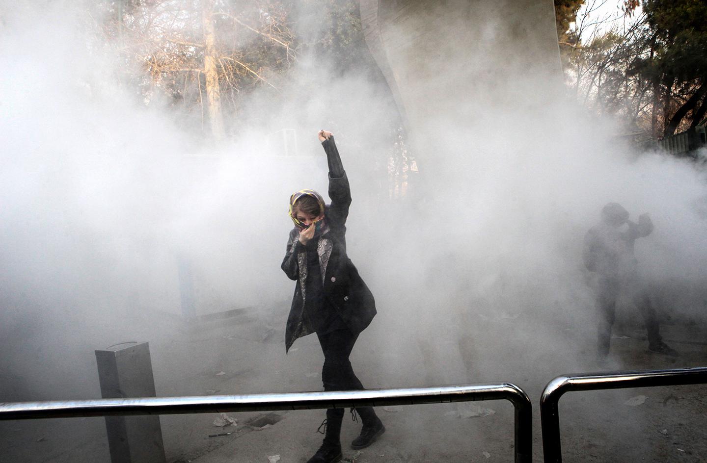 An Iranian woman raises her fist amid the smoke of tear gas at the University of Tehran during a protest driven by anger over economic problems, in the capital Tehran on December 30, 2017. Students protested in a third day of demonstrations sparked by anger over Iran's economic problems, videos on social media showed, but were outnumbered by counter-demonstrators.