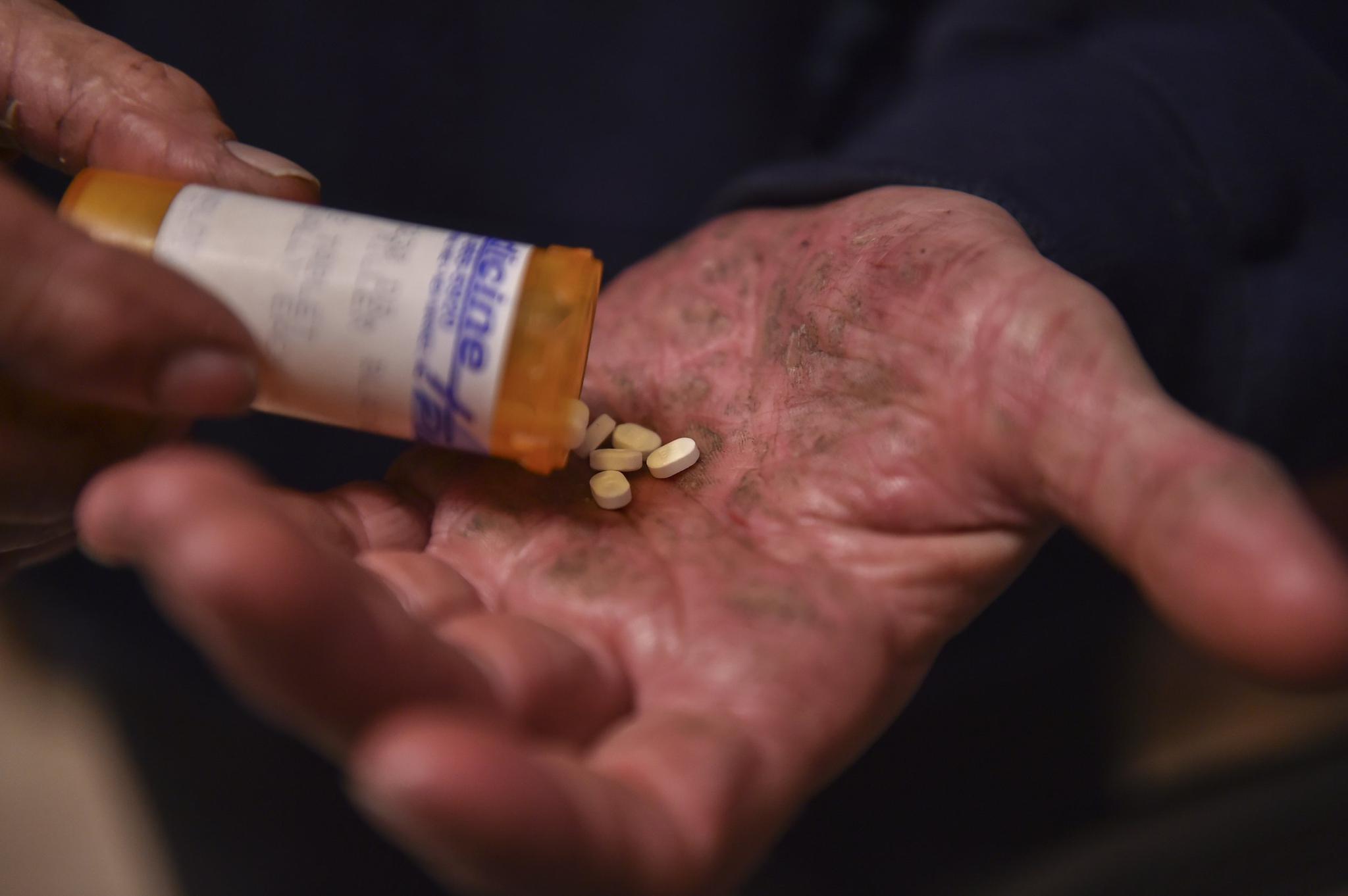 Greg Miller, with his severely chapped hands from working with glass, shows the suboxone medication that he takes daily on March 25, 2016 in Mt. Airy, Maryland.