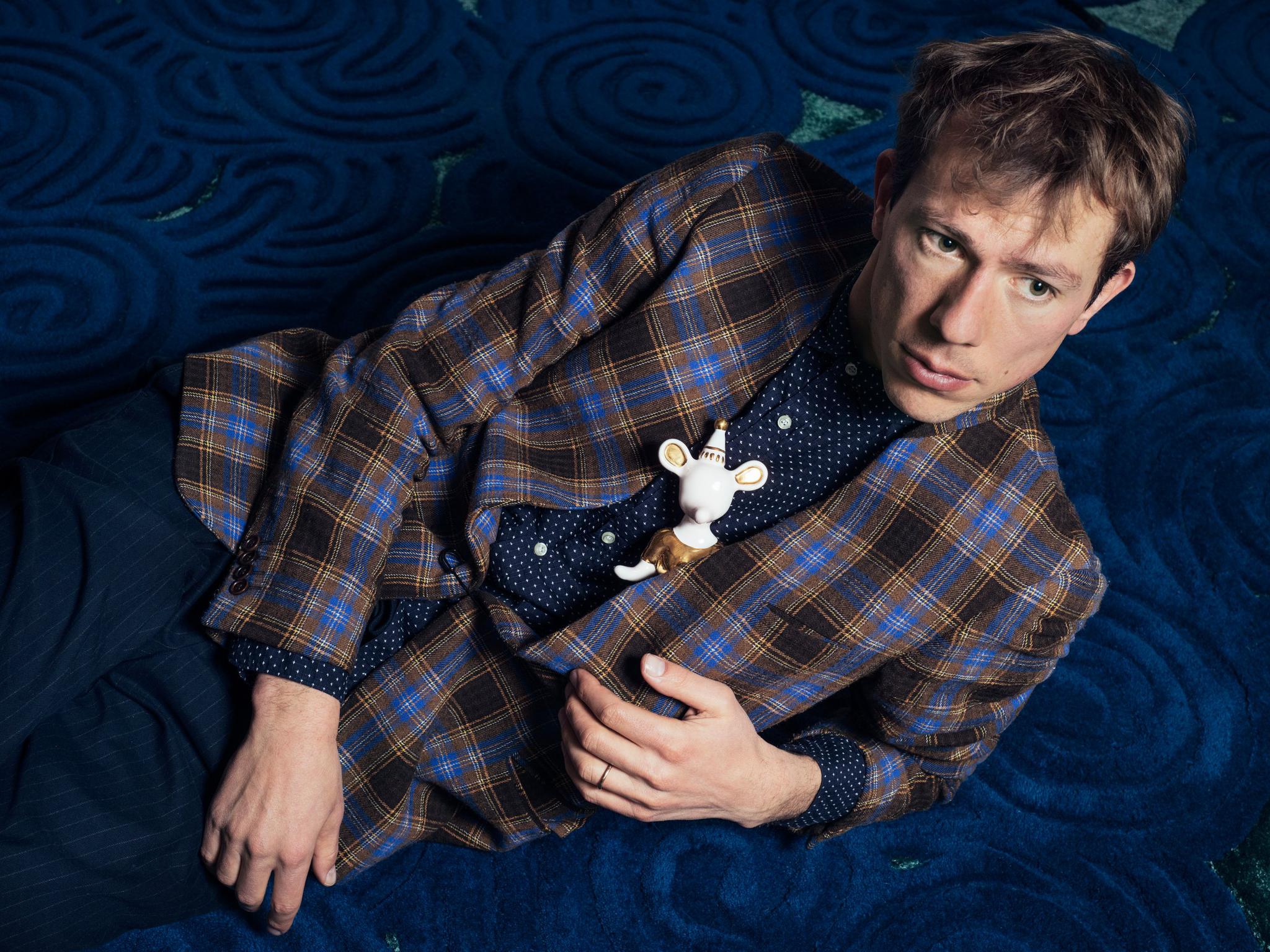 Matteo Cibic poses on River Moss, one of the carpets he created for Scarlet Splendour, with a ceramic character called The Princess.