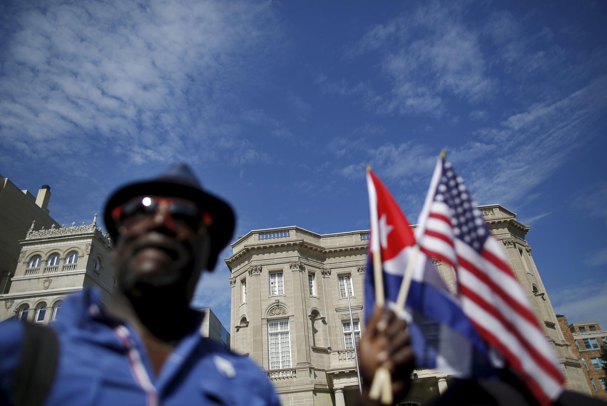 The newly reopened Cuban Embassy is seen in the background as a man holds U.S. and Cuban national flags on July 20, 2015.