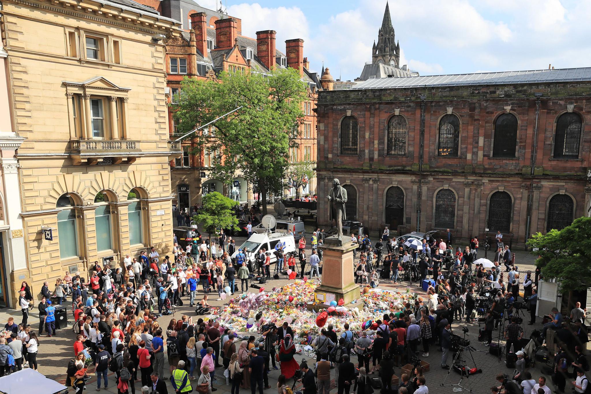 People look at flowers in St. Ann's Square, close to the Manchester Arena where a suicide bomber killed 22 people leaving a pop concert at the venue on Monday night.