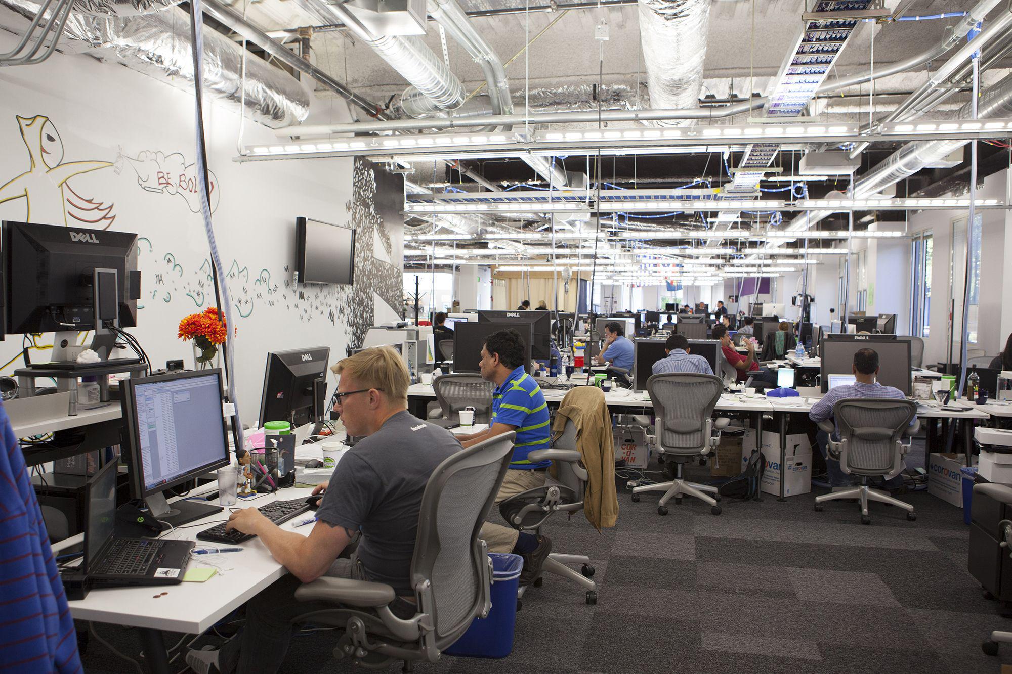 Scenes of daily work and life at Facebook , Inc. USA Headquarters in Menlo Park, California. View of employees at work in a typical unfinished looking workspace.