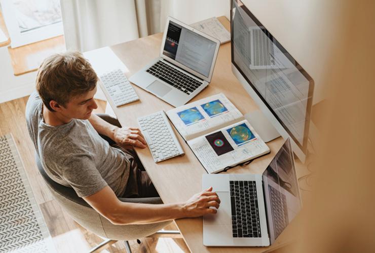 A Practical Guide To Maintaining Positive Body & Mindset For Winter WFH by Laura May. Photograph of a man working on three computers by Olia Danilevich