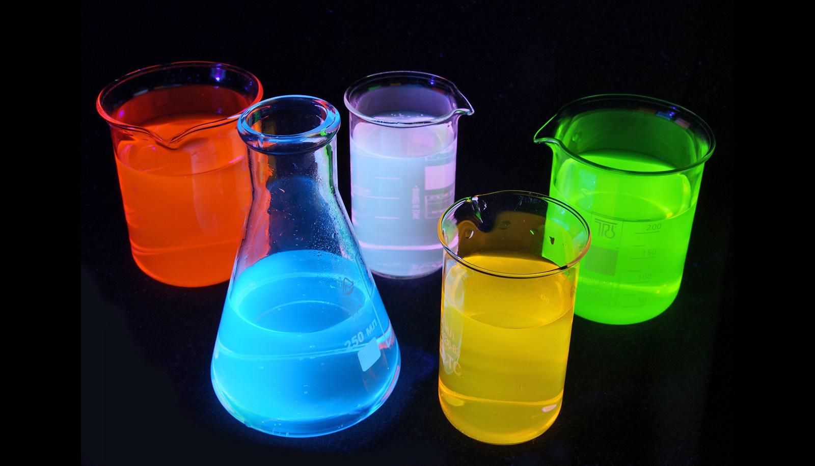 Fluorescent solutions in lab glass under UV-light.