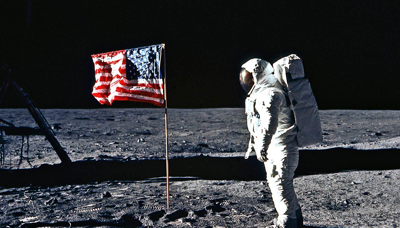 Astronaut looks at flag on the moon