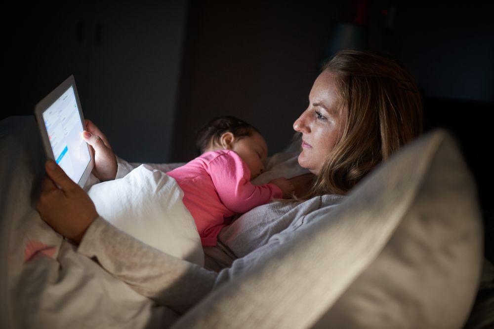 woman with ipad and baby at night