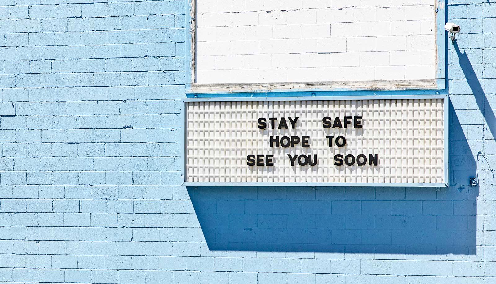 blue wall with sign, "stay safe hope to see you soon"