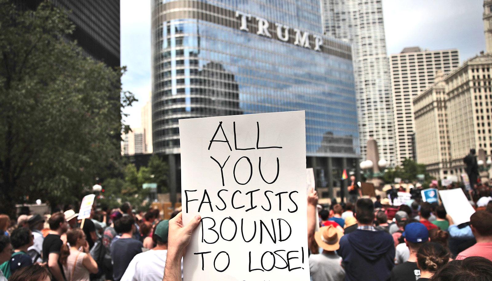 sign at protest reads "all you fascists bound to lose." Trump building in background