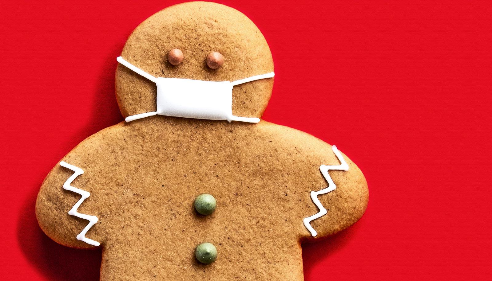 A gingerbread cookie person wears a medical mask made of frosting