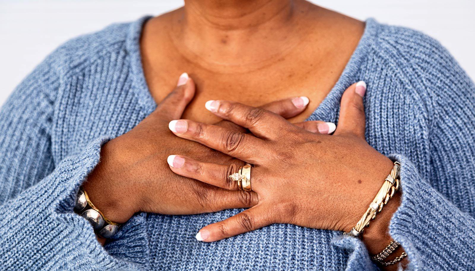 older woman lays hands on chest