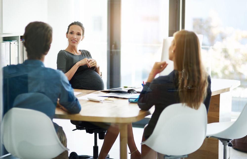 Pregnant Woman at Desk with Colleagues