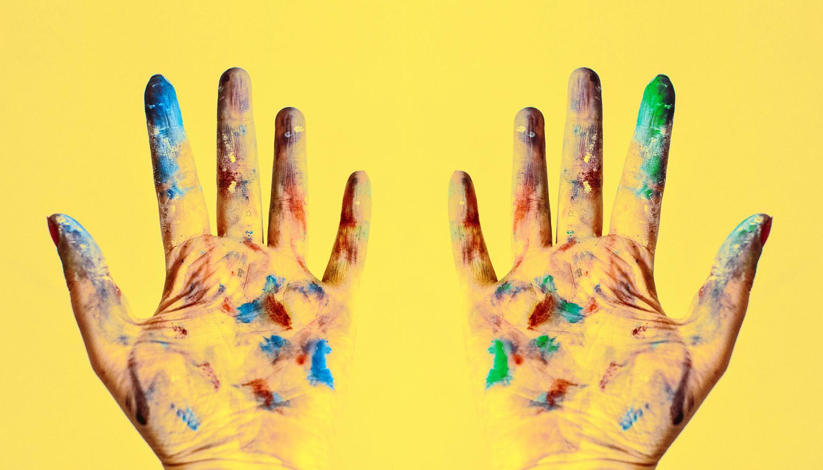 two paint-covered hands on yellow