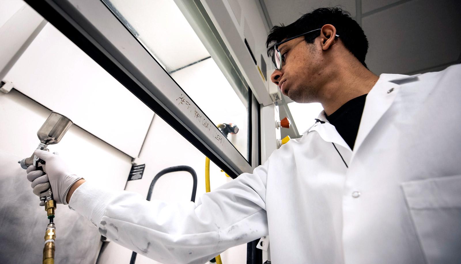 researcher in lab coat sprays coating