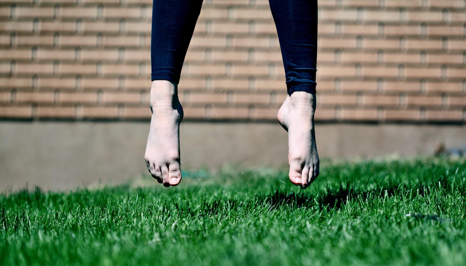 feet of jumping person on grass - human evolution concept