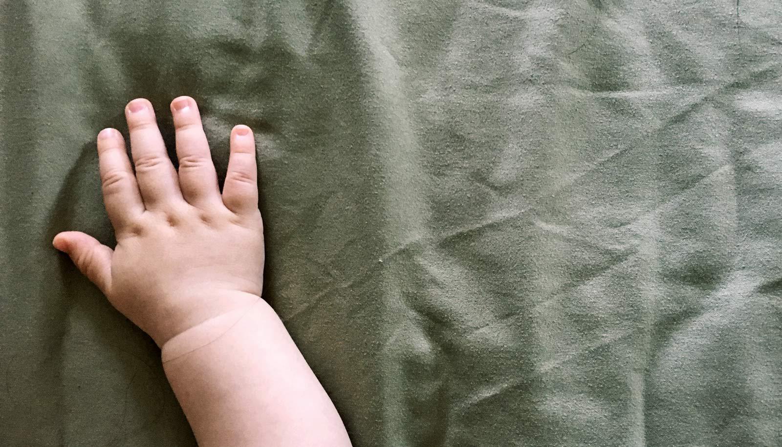 toddler's hand on green fabric