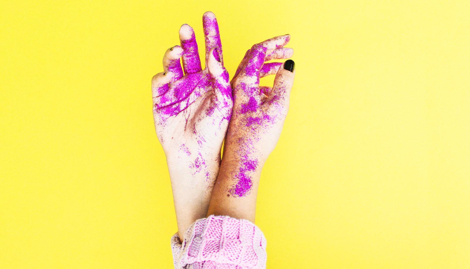 pink glitter on hands against yellow