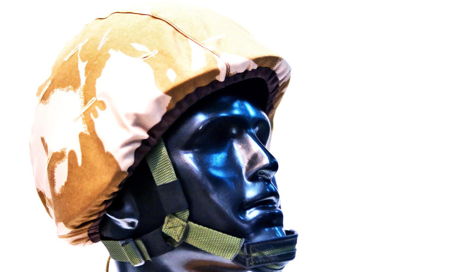 A mannequin wears a military-style helmet against a white background