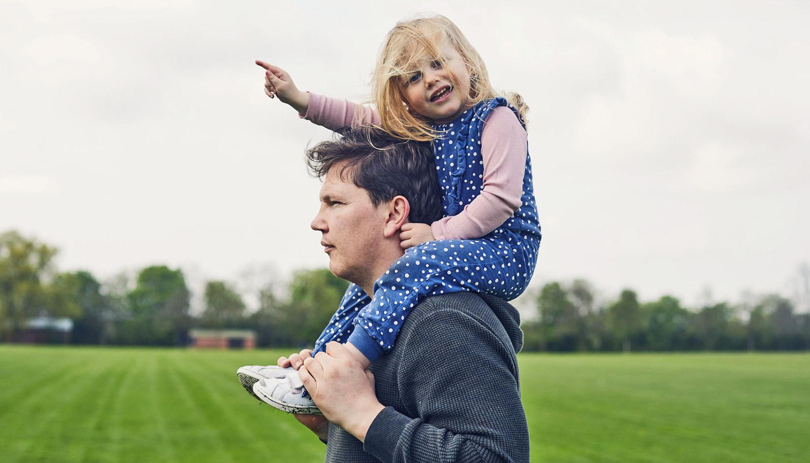 pointing toddler on stoic adult's shoulders