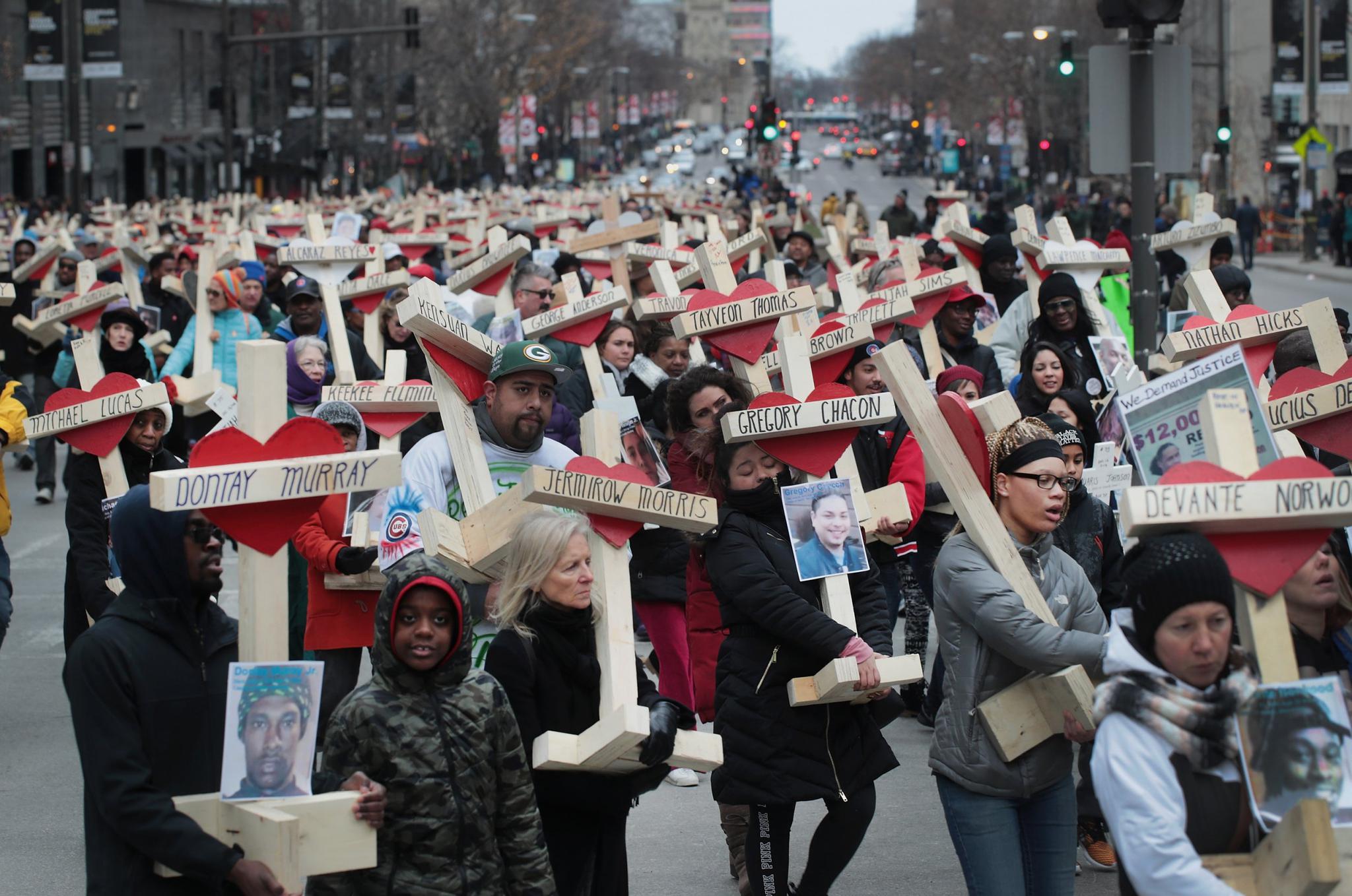 Residents, activists, and friends and family members of victims of gun violence march down Michigan Avenue carrying nearly 800 wooden crosses bearing the names of people murdered in the city in 2016 on December 31, 2016 in Chicago, Illinois. Nearly 800 people were murdered in the city last year and more than 4,000 shot as the city copes with its most violent year in two decades.