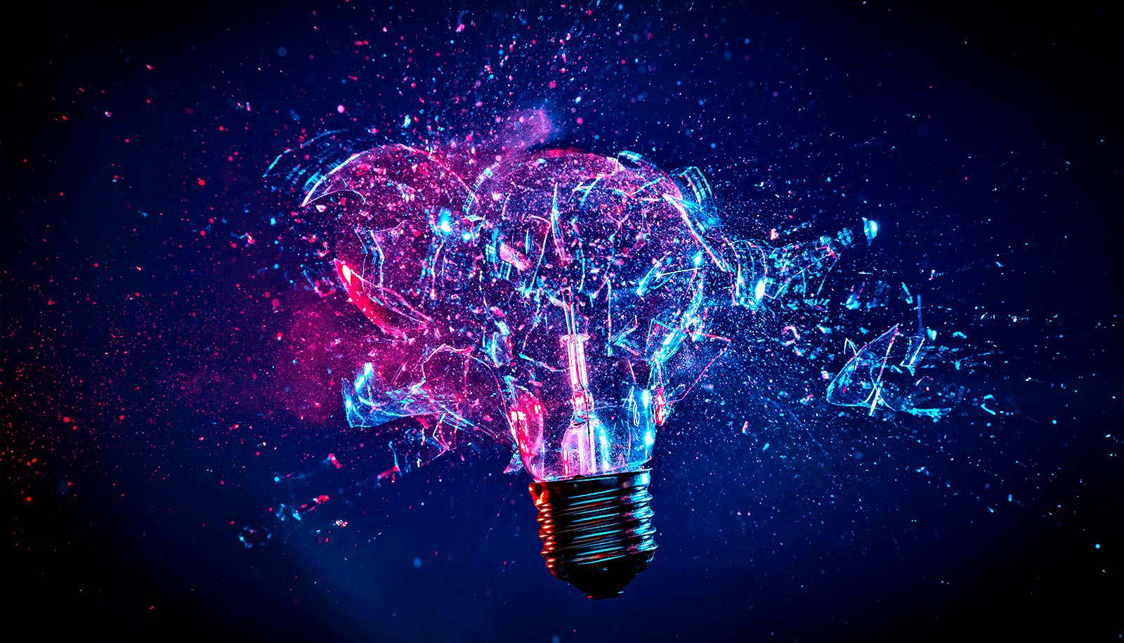 A lightbulb explodes with pink and blue light shining through it