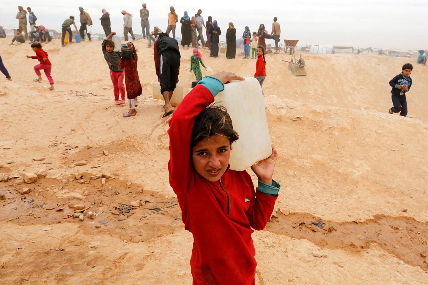 Syrian refugees collect water while after crossing into Jordanian territory, near the town of Ruwaished, east of the capital Amman, May 4, 2016.