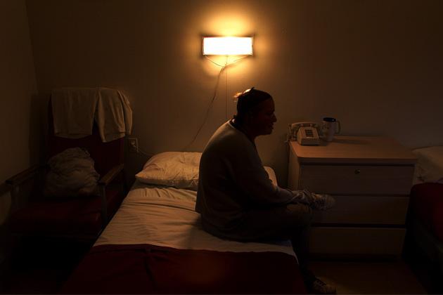 A resident sits on her bed at Oceanview Manor, an adult home in Brooklyn, New York, in September 2001. Three years ago, a federal judge ordered residents be moved out of adult homes like Oceanview Manor. (Nicole Bengiveno/The New York Times/Redux Pictures)