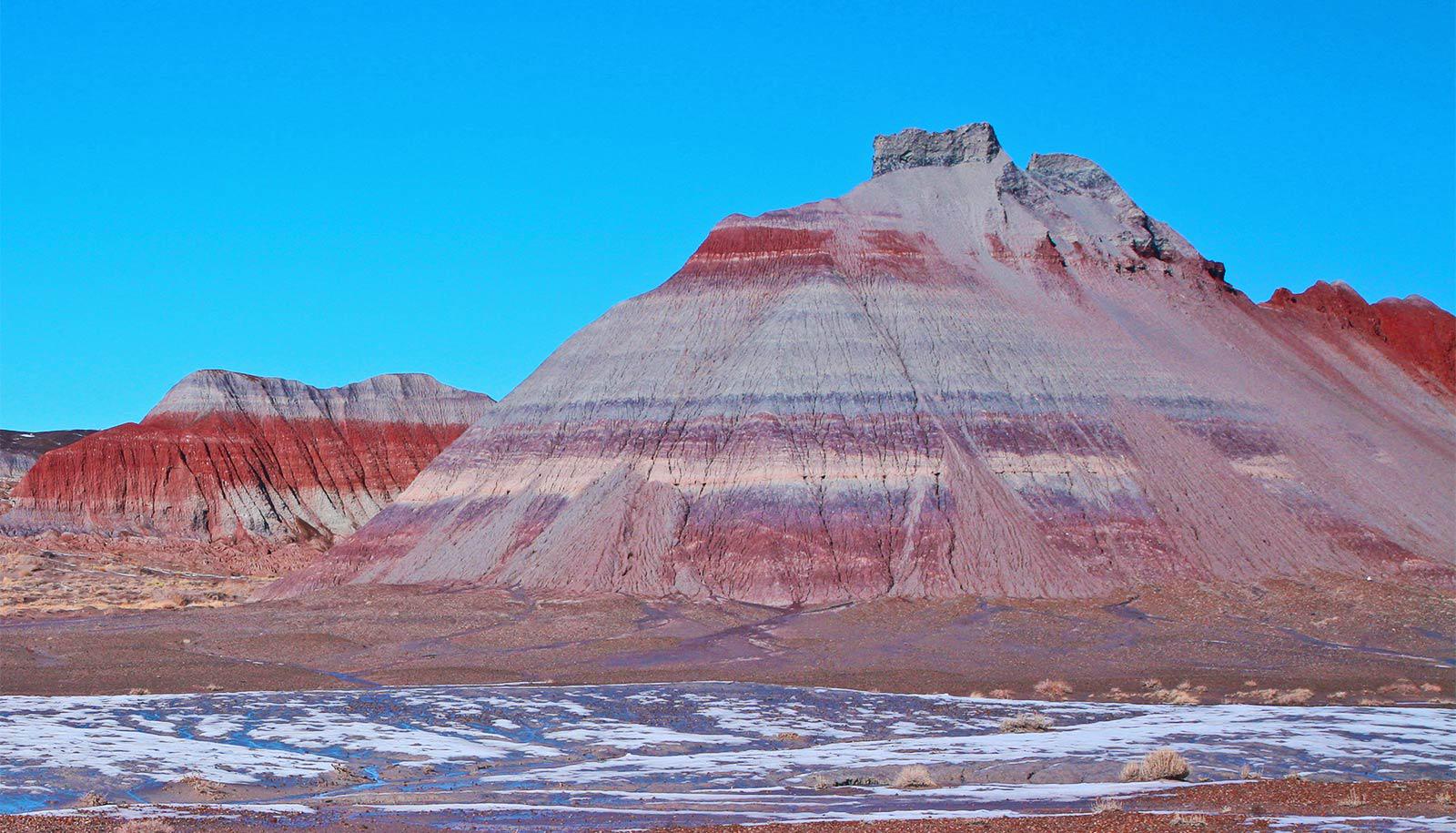 Red rocks can be seen in streaks on large, rocky hills