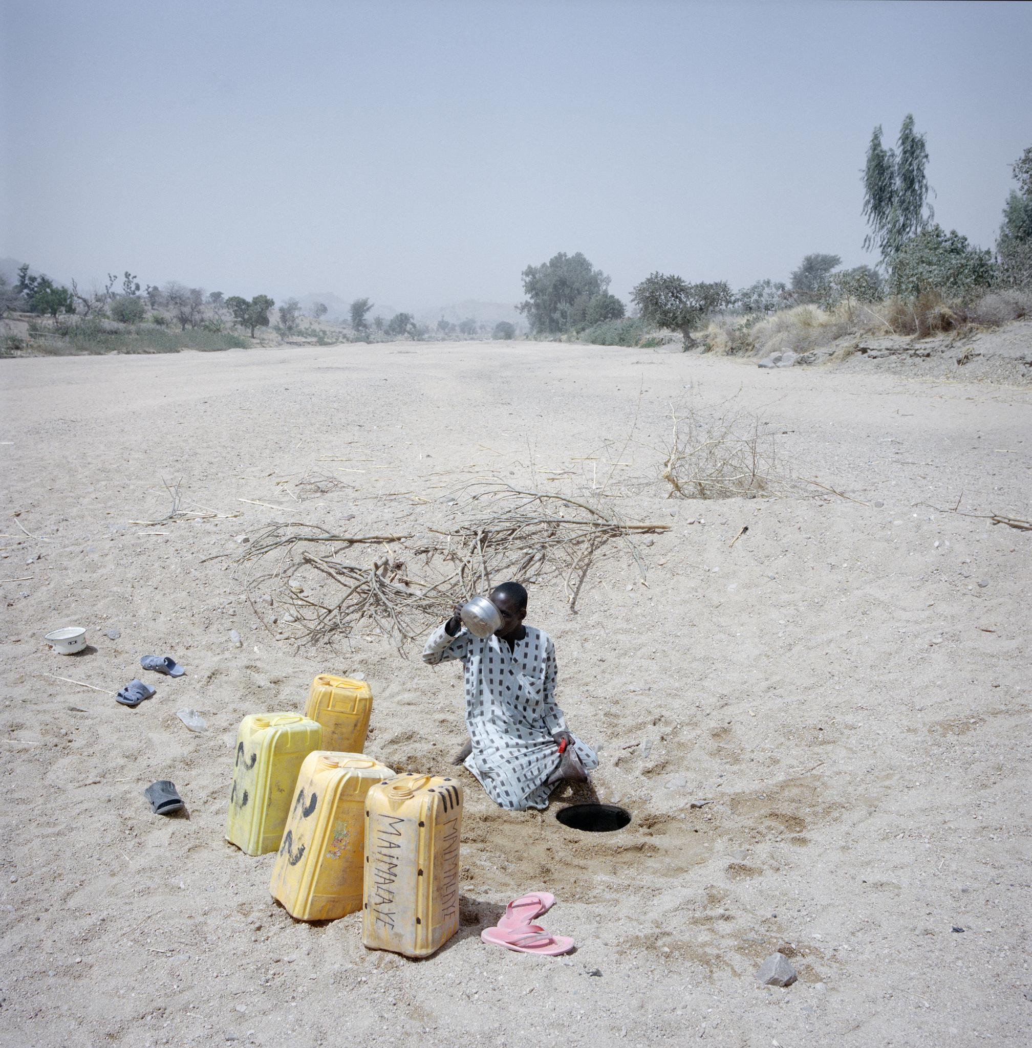 Al Hadji Dalla, a 25-year-old Nigerian refugee living in Minawao, in the extreme north of Cameroon, collects water from a hole in a dry riverbed. He fled Nigeria four years ago and has been collecting water here every day for the last two years. A changing climate means Cameroon's rainy season falls two months shorter, making the struggle for water even harder.