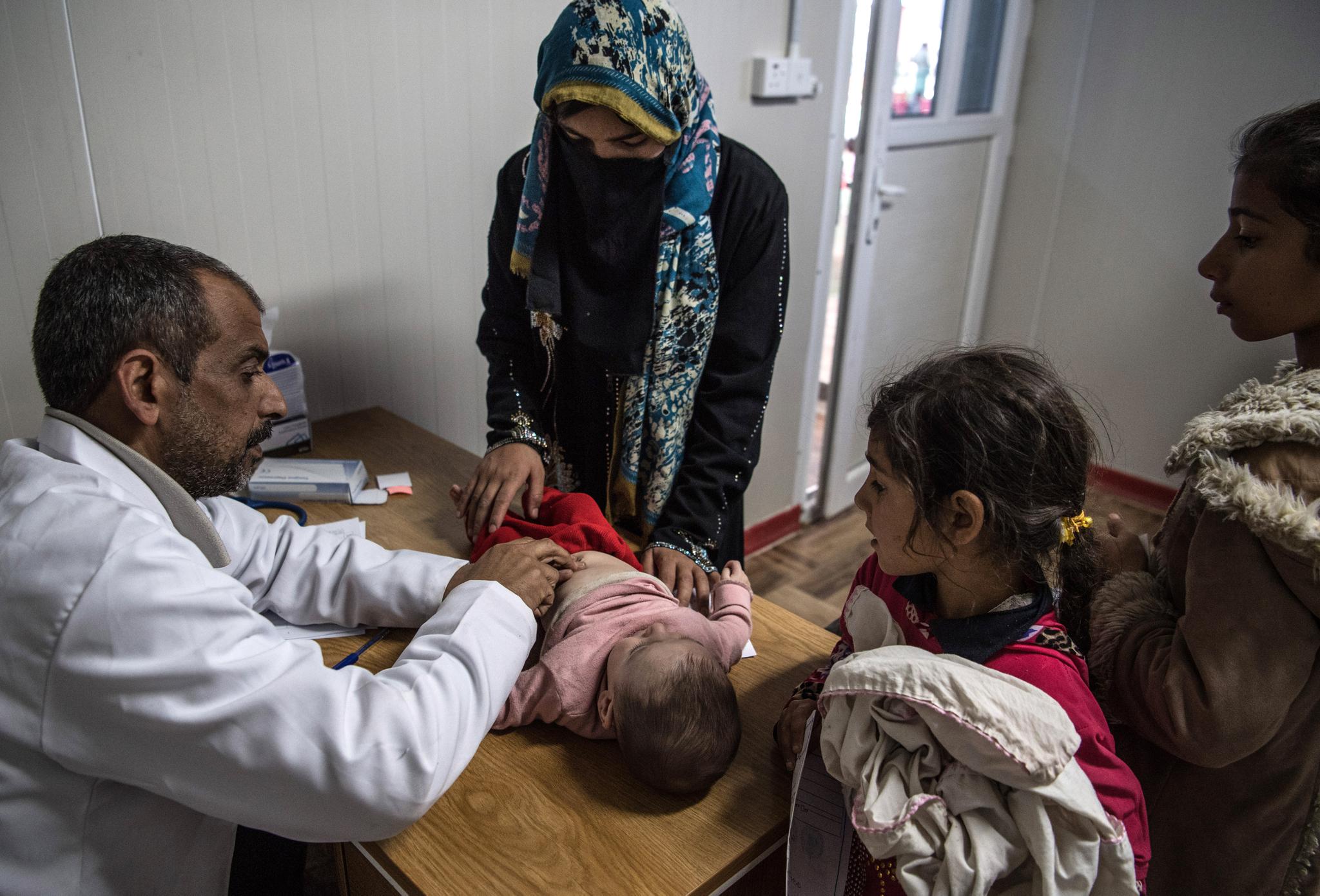 Iraq's brain drain has created an extreme shortage of in-country doctors, like this one, treating a little boy in Hamam al-Alil refugee camp on April 5th.