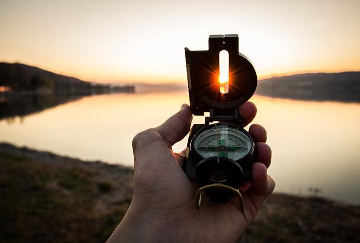 How to Course-Correct Your Future by Dain Heer. Photograph of a hand holding a compass in the sun, by Tim Graf.
