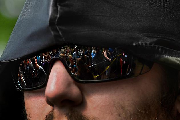 A crowd of protestors are reflected in the sunglasses of a member of the Ku Klux Klan in Justice Park in Charlottesville, Virginia. (Michael S. Williamson/The Washington Post via Getty Images)