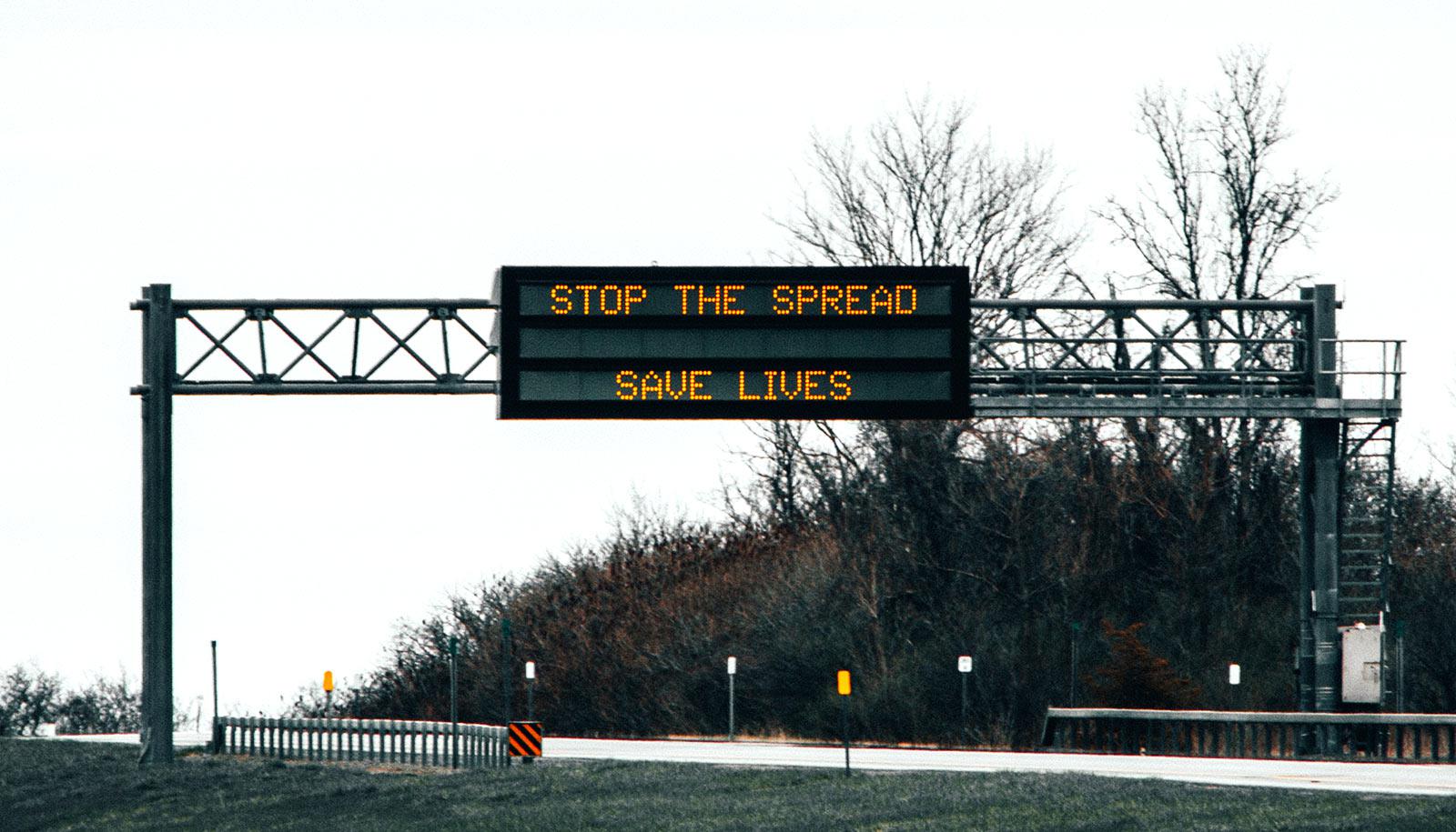 sign over highway says "stop the spread save lives"