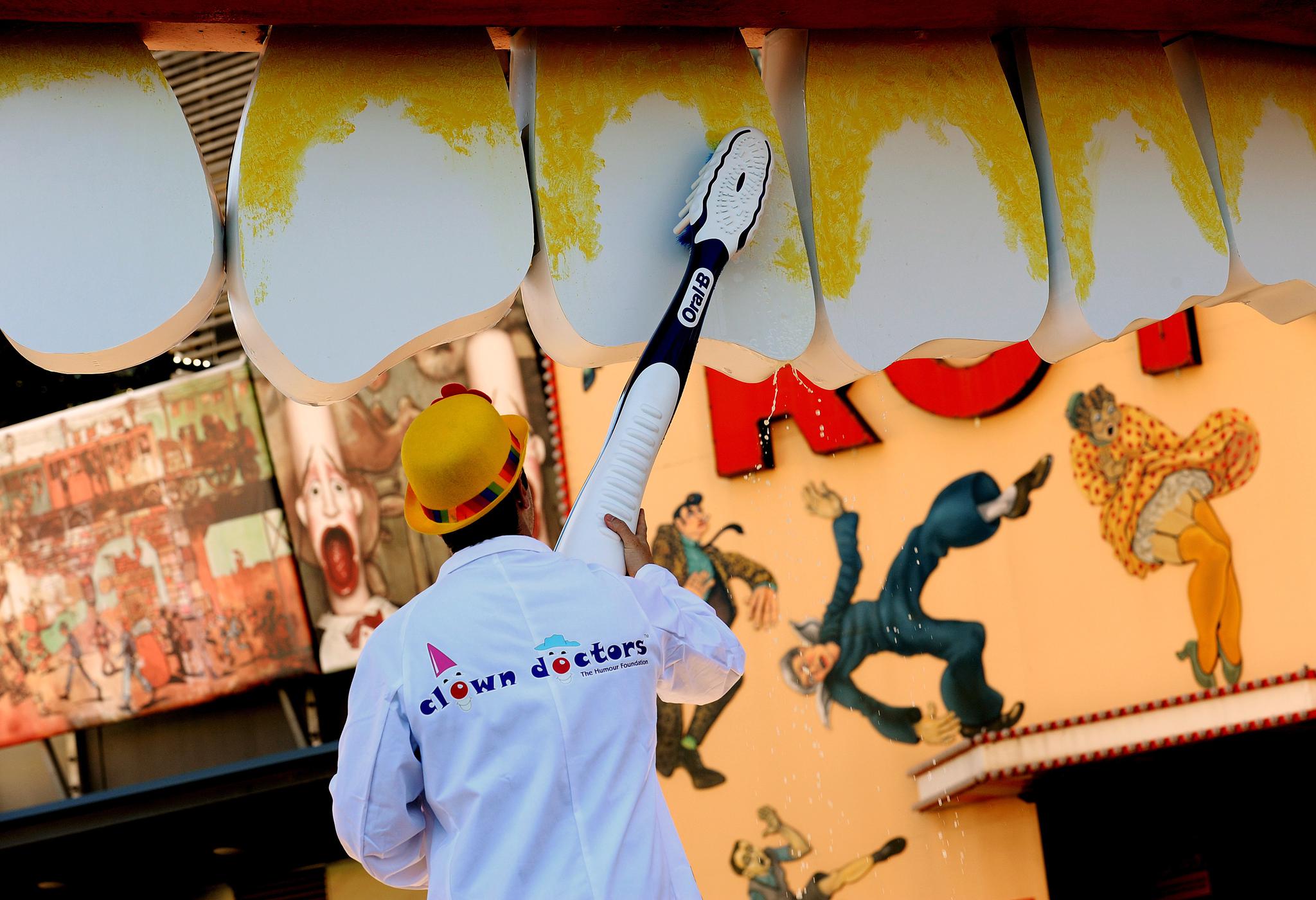 On Australia's National Smile Day, clown doctor, Dr. B. Looney, uses a giant toothbrush to clean the teeth on the face at the entrance to Luna Park in Sydney in 2010.