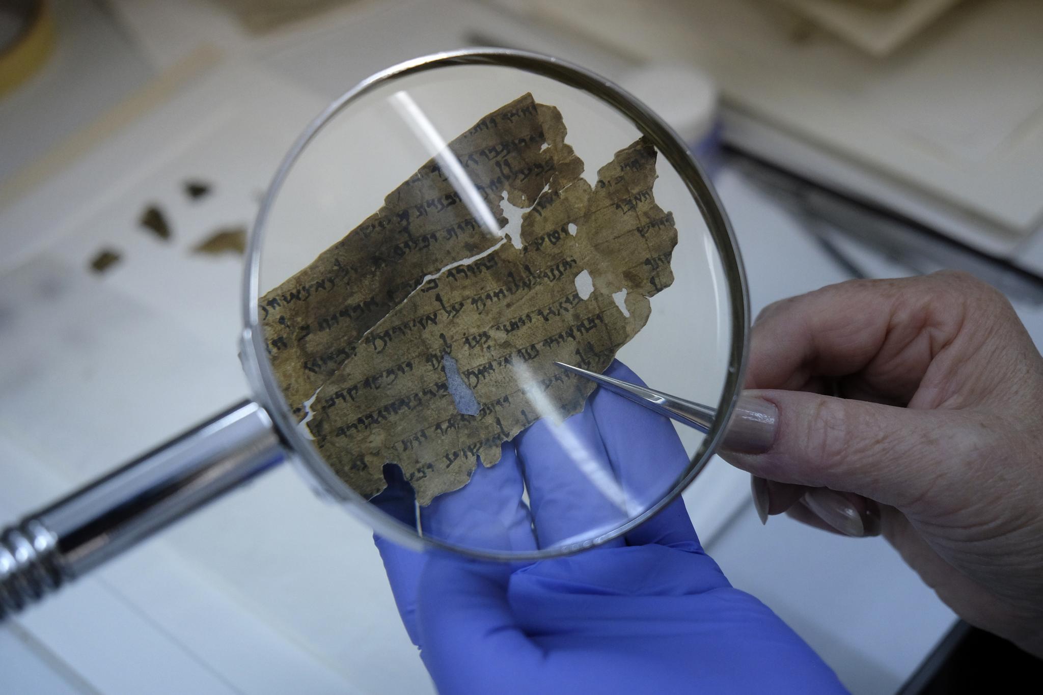 An employee of the Israel Antiquities Authority sews fragments of the Dead Sea scrolls in a preservation laboratory at the Israel Museum in Jerusalem on July 20, 2015.