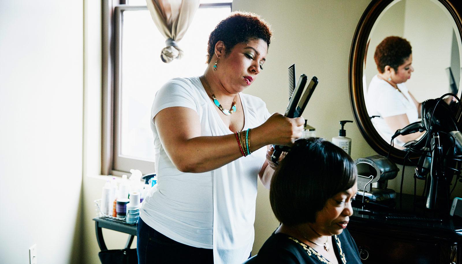 black woman styles customer's hair