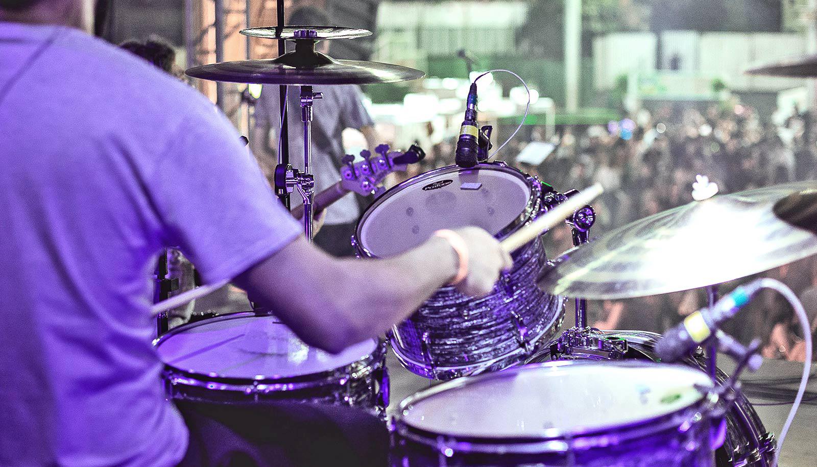 A drummer plays on stage for a crowd